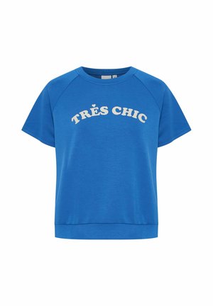 Zils kokvilnas T-krekls ar īsām raglanu piedurknēm. Priekšpusē liela balta teksta frāze "TRÈS CHIC".