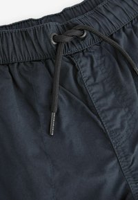 Marineblaue Badeshorts mit elastischem Bund, verstellbarem schwarzen Kordelzug, glatter Textur und kontrastierenden Nähten entlang der Seitennaht.