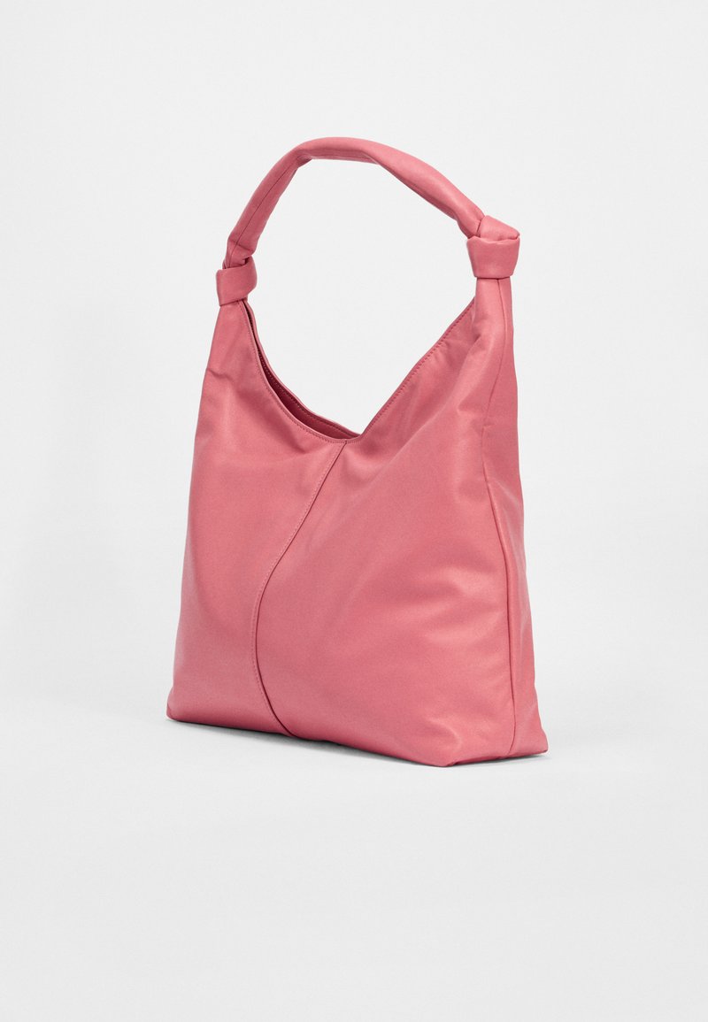 Rosa, weiche Stofftasche mit geschwungenem Design, geknotetem Griff und subtilen Nahtdetails. Leicht und geräumig für den täglichen Gebrauch.