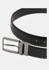 Cintura nera con motivo a pattern e fibbia in metallo di tonalità argento. La fibbia presenta una forma rettangolare e un marchio impresso. Materiale testurizzato su tutta la superficie.