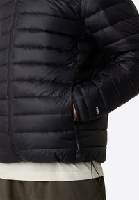 Black padded jacket featuring a smooth fabric, zip closure, pockets, and adjustable drawstring at the hem. Lightweight with a sleek design.