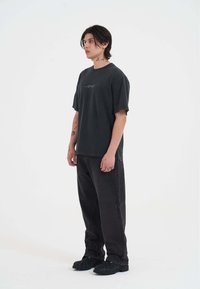 Sort oversized t-shirt med rund halsudskæring og korte ærmer. Sammen med vide sorte jeans med synlige syninger.