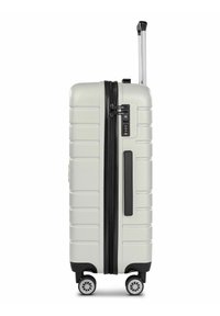Valigia rigida bianca con accenti neri, superficie testurizzata, scanalature verticali, lucchetto a combinazione e quattro ruote per la mobilità.