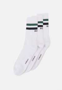 Weiße Crew-Socken im Dreierpack, mit grünen und schwarzen Horizontalstreifen am oberen Rand und schwarzem Text "BON." Aus strukturierter Baumwolle.