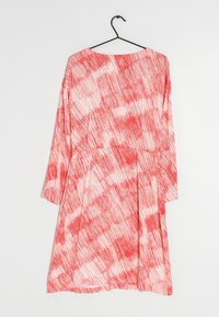 Rotes und weißes Kleid mit einem Muster aus dünnen, streifigen Linien. Langen Ärmeln und einer lockeren Passform mit rundem Ausschnitt. Hängt an einem schwarzen Haken.