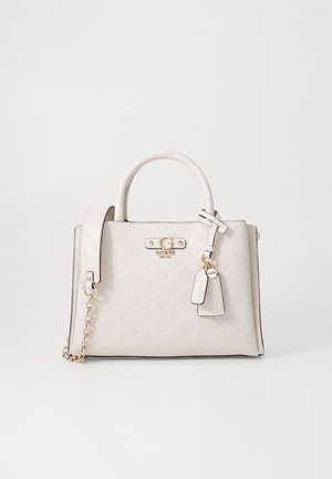 Witte Guess handtas met geprikt logo patroon, bovenhandvatten, afneembare schouderriem en hangende merklabels op een effen achtergrond.