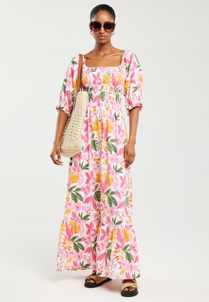 Robe maxi en tissu rose avec des motifs floraux jaunes et verts ; décolleté carré, manches bouffantes, taille smockée et ourlet évasé.