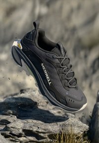 Black Merrell sneaker with a textured synthetic upper, GORE-TEX label, lacing system, and a white and grey outsole. Vibram logo visible.
