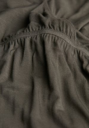 Dunkelolivgrüner Stoff mit weicher, dehnbarer Textur. Verfügt über gerüschte Nähte entlang des Randes, die einen drapierten Effekt erzeugen.