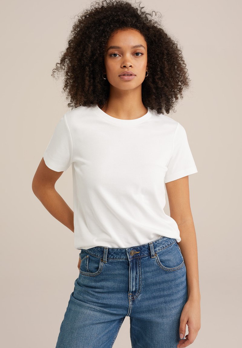 Witte katoenen t-shirt met een ronde hals en korte mouwen, gedragen met blauwe denim jeans, met een klassieke snit en een soepele textuur.