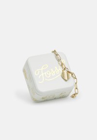 Square white tin box with gold accents featuring the word "Fossil"; includes a gold chain with a heart-shaped charm.