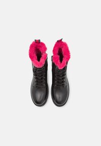 Bottes en cuir noir à lacets avec doublure intérieure duveteuse rose vif, vues de dessus sur un fond blanc uni.