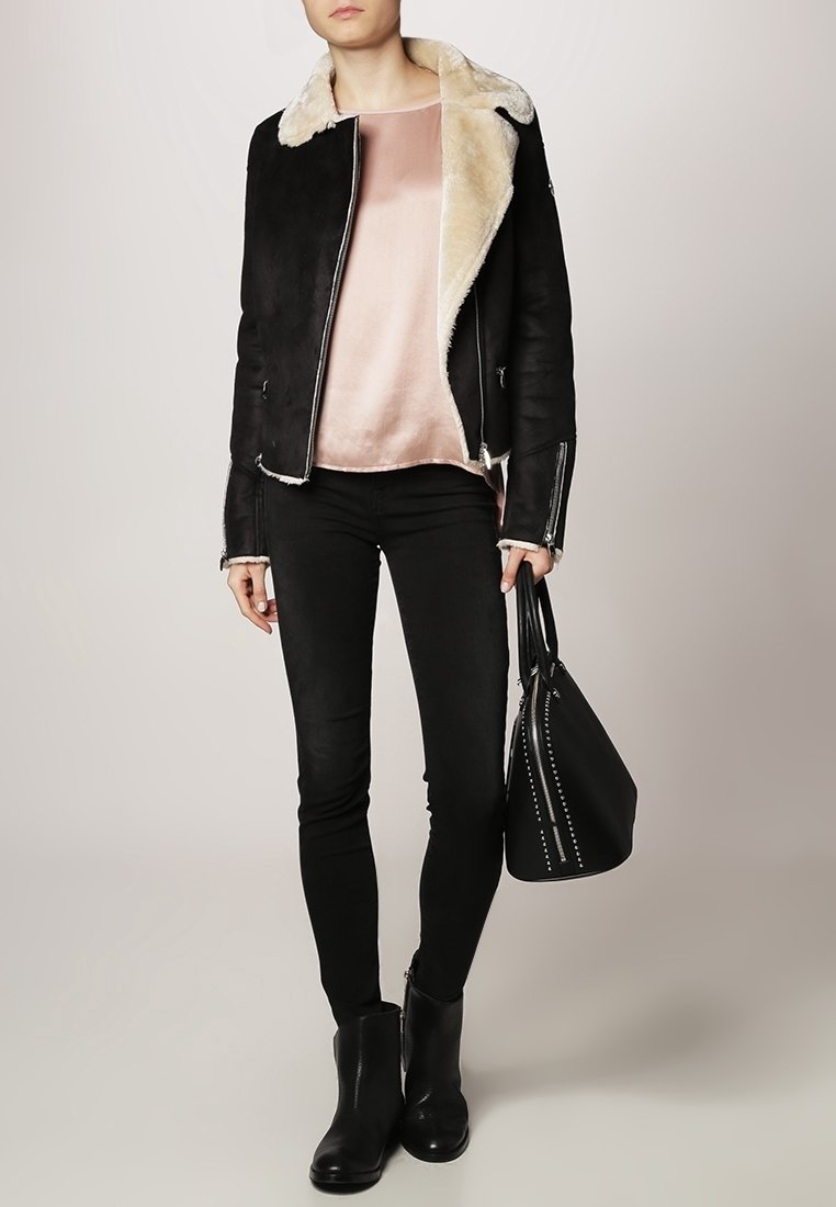 Svart lammskinnsjacka med krämfärgad foder, lager på lager över en rosa satinblus. Bärs med svarta skinny jeans och ankelboots. Svart väska med hårdvaruaccents.