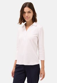 Maglietta polo bianca con colletto, maniche a tre quarti e una chiusura a due bottoni. Tessuto in cotone morbido e dalla consistenza liscia. Design semplice e classico.