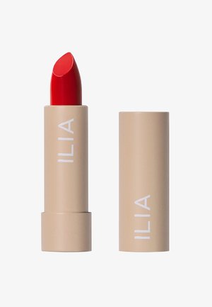 ILIA Lippenstift in einer beigen Tube mit glatter Oberfläche, ausgestattet mit einer leuchtend roten Spitze. Schlichte Markenpräsenz in Weiß auf der Tube.