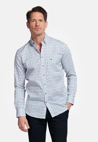 Chemise boutonnée en bleu clair, présentant un petit motif géométrique multicolore. Manches longues avec poignets à boutons et col standard.