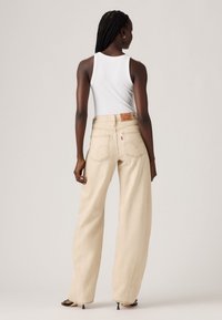 Beige wijde jeans met een hoge taille, textuurdenim en zichtbare stiksels. Voorzien van klassieke achterzakken en een leren label met merklogo.