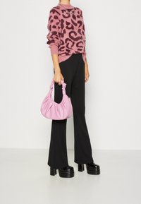 Dunrosa tröja med ett mörkt leopardmönster, svarta utsvängda byxor, rosa texturerad väska med samlade handtag, och tunga svarta plattformshöga klackar.