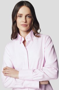 Jasnoróżowa koszula zapinana na guziki, wykonana z gładkiego materiału. Posiada klasyczny kołnierzyk oraz długie rękawy z mankietami na guziki, prezentując czysty design.