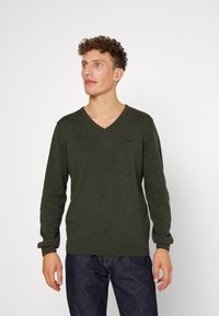 Dunkelgrüner Strickpullover mit V-Ausschnitt, langen Ärmeln und gerippten Bündchen sowie Saum. Verfügt über ein kleines Logo auf der Brust.