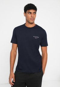 Navy blue short-sleeve T-shirt made of cotton, featuring a front logo print with white text and a small American flag accent.