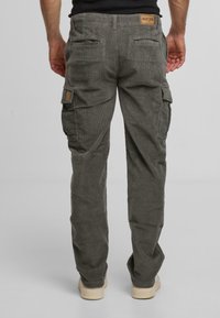 Graue Corduroy-Cargo-Hosen mit zwei Seitentaschen, gerippter Textur und einem Logo-Patch am hinteren Bund. Gerade Beinform.