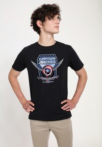 Camiseta de algodón negra con un diseño gráfico del escudo de Capitán América, con alas, acentos en azul y rojo, y patrones de estrellas blancas.