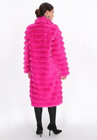 Faux fur coat in bright pink, featuring a ribbed texture and high collar. Paired with black leather leggings and black pointed ankle boots.