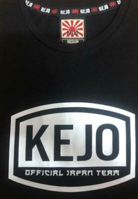 Maglietta nera con un grande logo bianco "KEJO" sul davanti. Lo scollo presenta un dettaglio rosso e bianco con il nome del marchio. Tessuto di cotone.