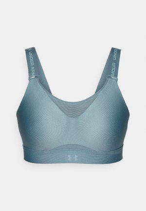 Soutien-gorge de sport dans une teinte de bleu muted, fabriqué en tissu lisse et extensible. Il dispose de bretelles réglables avec un logo et d'un design sans coutures.