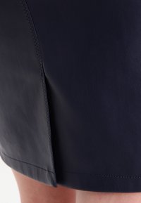 Námořnická kožená sukně s přiléhavým střihem, hladkým povrchem a bočním rozparkem s kontrastním prošitím.