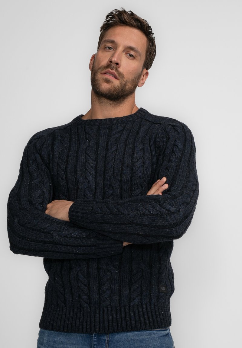 Dunkelblaues, kabelgestricktes Sweatshirt mit Rundhalsausschnitt, gerippten Bündchen und Detailarbeitung am Körper; aus einem dicken, strukturierten Material gefertigt.