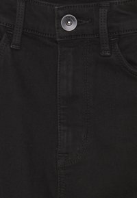 Jeans de mezclilla negra con cierre de botón frontal, costura vertical y bolsillos laterales con una textura suave y un diseño ajustado.