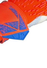 Gant orange vif en texture avec des accents synthétiques bleus. Présente des motifs géométriques et un design flexible pour un meilleur grip et une meilleure liberté de mouvement.