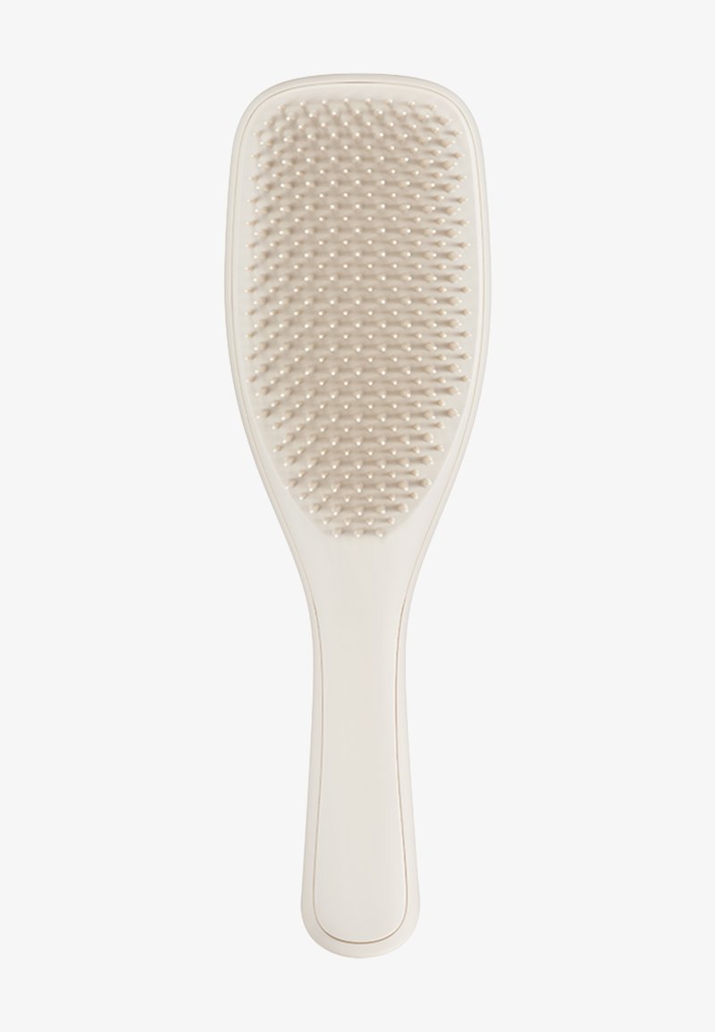 Brosse à cheveux à paddle avec un manche en plastique lisse et crémeux de couleur blanche. La tête de la brosse présente des poils doux à pointes rondes disposés en motif de grille.