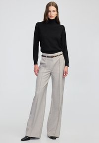 Maglione aderente nero a collo alto. Pantaloni a gamba larga grigio chiaro con una sottile trama e cuciture frontali, abbinati a una cintura marrone scuro con hardware dorato.