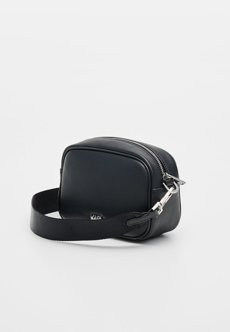 Bolso bandolera de cuero negro con forma rectangular, cierre de cremallera plateado y correa de tela ajustable. Textura suave y diseño minimalista.