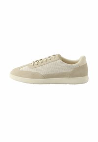 Zapatillas beige con parte superior de ante y malla, punta redonda, suela plana de goma y cierre de cordones sencillo. Detalles texturizados en los laterales.