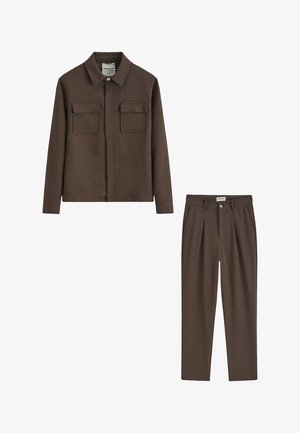 Veste marron à boutons avec deux poches poitrine à rabat, assortie à un pantalon plissé assorti.