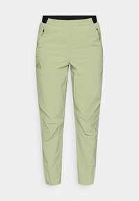 Ανοιχτό πράσινο, στενό παντελόνι με μαύρη ελαστική μέση, τσέπες με φερμουάρ και λογότυπο στο αριστερό πόδι. Λείο, ελαφρύ ύφασμα.