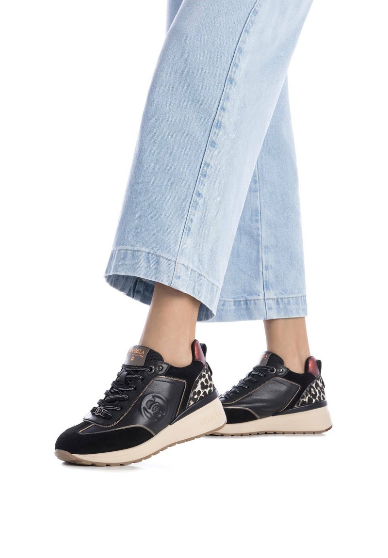 Schwarze und tanfarbene Sneaker mit Obermaterial aus Wildleder und Leder, mit Akzenten im Leopardenmuster und kontrastierendem roten Fersenbereich. Enthält ein Schnürdesign und Logodetails.