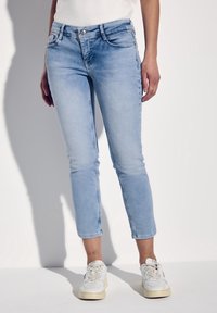 Ljusblå denimjeans med slim fit, medelhög midja och kort längd, med klassisk femficksdesign och synlig sömnad.