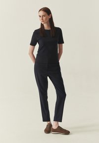 Haut bleu marine à manches courtes et pantalon ajusté, assortis à des baskets en daim marron. Design simple avec une texture lisse, créant un look harmonieux.