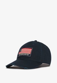 Gorra azul marino de algodón, con un parche delantero que muestra una bandera americana y el texto "SUPERDRY", visera desgastada y parte trasera ajustable.