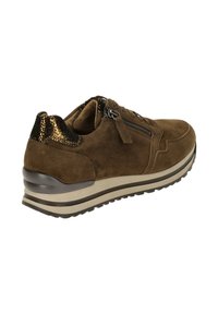 Bruine suède sneaker met zwarte metallic accenten, zijklep sluiting en een dikke witte streep zool. Gestructureerde hak voor extra grip.