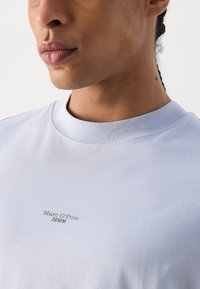 Ljusblå t-shirt med kort ärm, tillverkad av mjuk bomull, med rund halsringning och en liten "Marc O'Polo DENIM"-logotyp på framsidan.