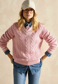 Roosa kabeli kudumisega sviiter v-kaelusega ja soonikservaga, seljas denimist särk, koos helesiniste teksade ja beeži mütsiga.