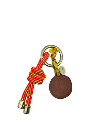 Porte-clés en métal avec des cordons noués rouges et jaunes et un pendentif circulaire marron gravé d'un symbole de paix.