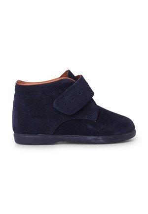 Botas de ante azul marino hasta el tobillo con correa de velcro, acentos perforados, punta redonda y una suela de goma duradera con un ligero tacón.
