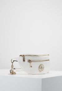 Valkoinen nahkainen vyölaukku, jossa on kaksi vetskaria, kultaiset yksityiskohdat ja koristeellinen logo-medaali edessä.